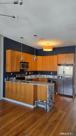 a large kitchen with granite countertop a stove a sink and a wooden floor