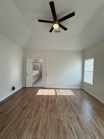 a view of empty room with wooden floor and fan