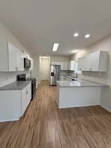 a large kitchen with cabinets wooden floor and stainless steel appliances