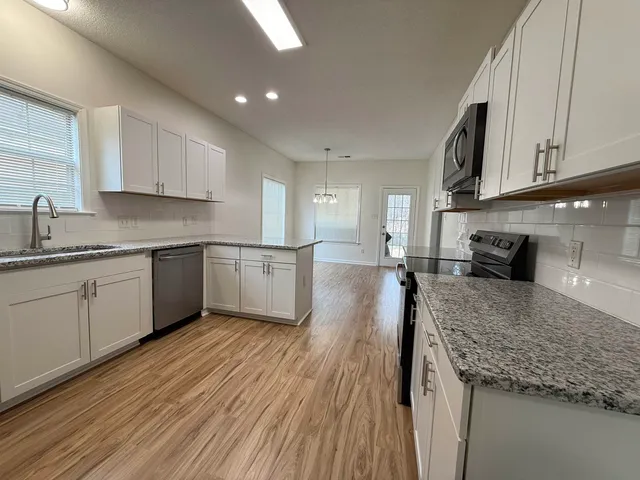 a kitchen with stainless steel appliances granite countertop a sink a stove top oven a counter space and cabinets