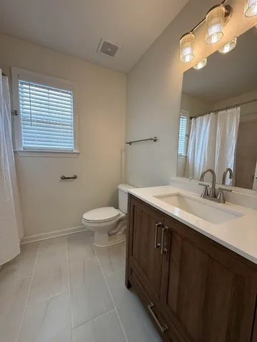 a spacious bathroom with a granite countertop sink a toilet and a mirror