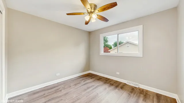 an empty room with a window and a ceiling fan