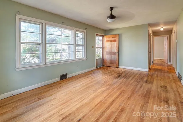a view of an empty room with wooden floor and a window