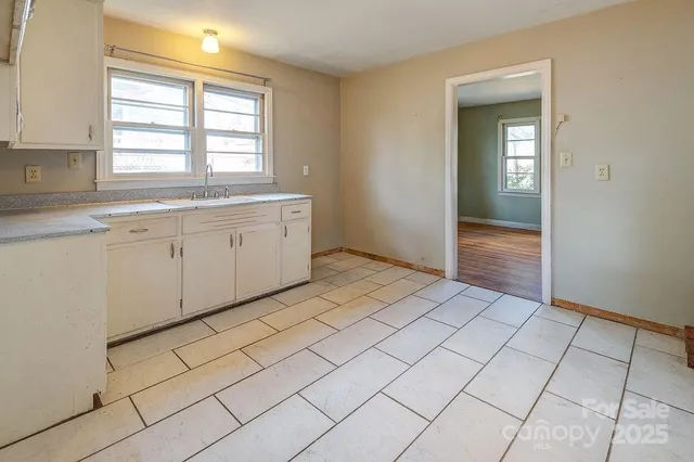 a view of a kitchen with white cabinets and a window