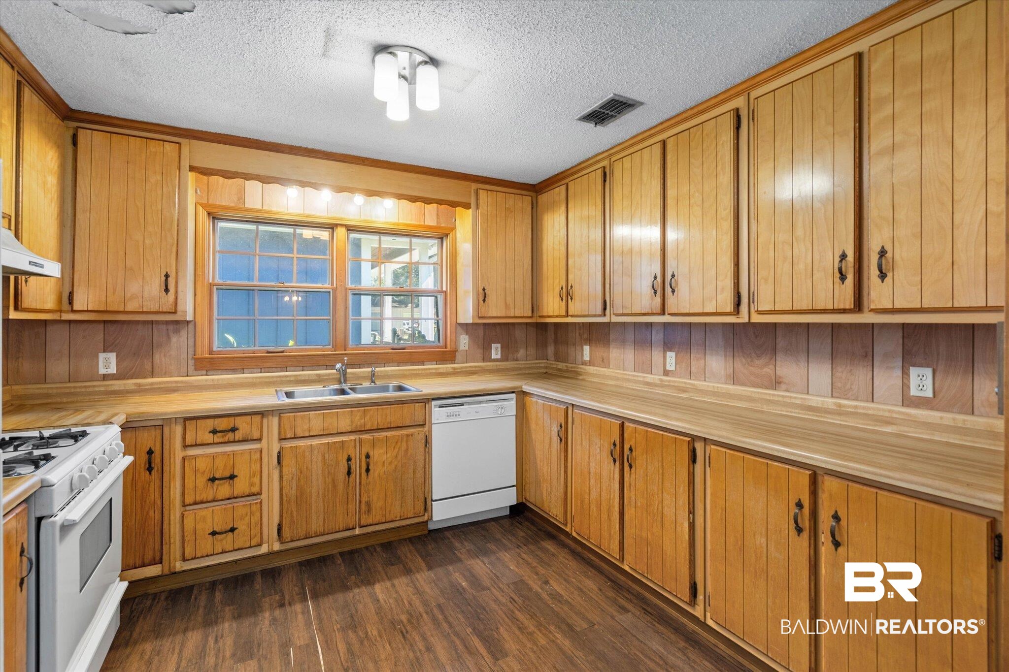 5503 Darring Street Satsuma, AL 36572 - Photo 7 of 31 Kitchen with white appliances, dark wood finished floors, light countertops, a textured ceiling, and brown cabinetry