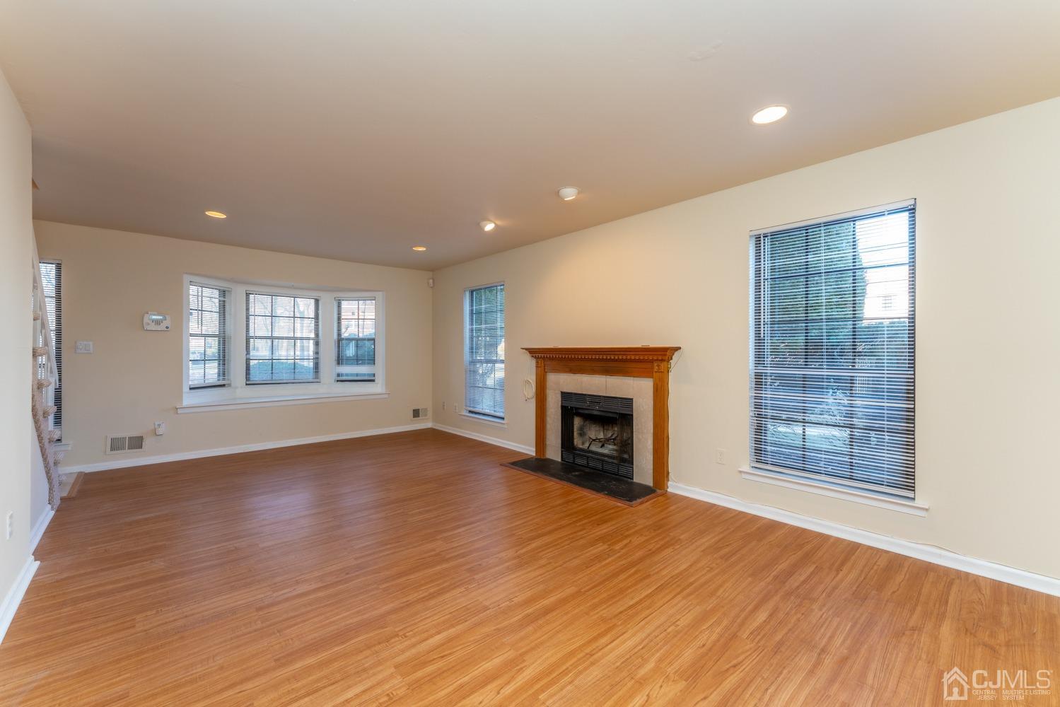 3204 Stonehedge Road Edison, NJ 08820 - Photo 7 of 22 an empty room with wooden floor fireplace and windows