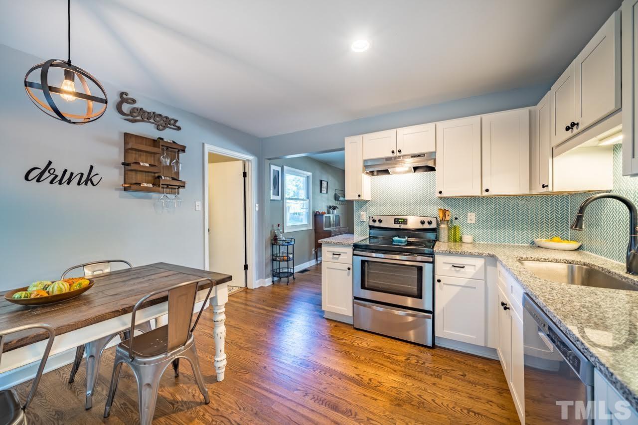1105 Somerset Road Raleigh, NC 27610 - Photo 6 of 19 a kitchen with granite countertop a stove a sink dishwasher a dining table and chairs with wooden floor