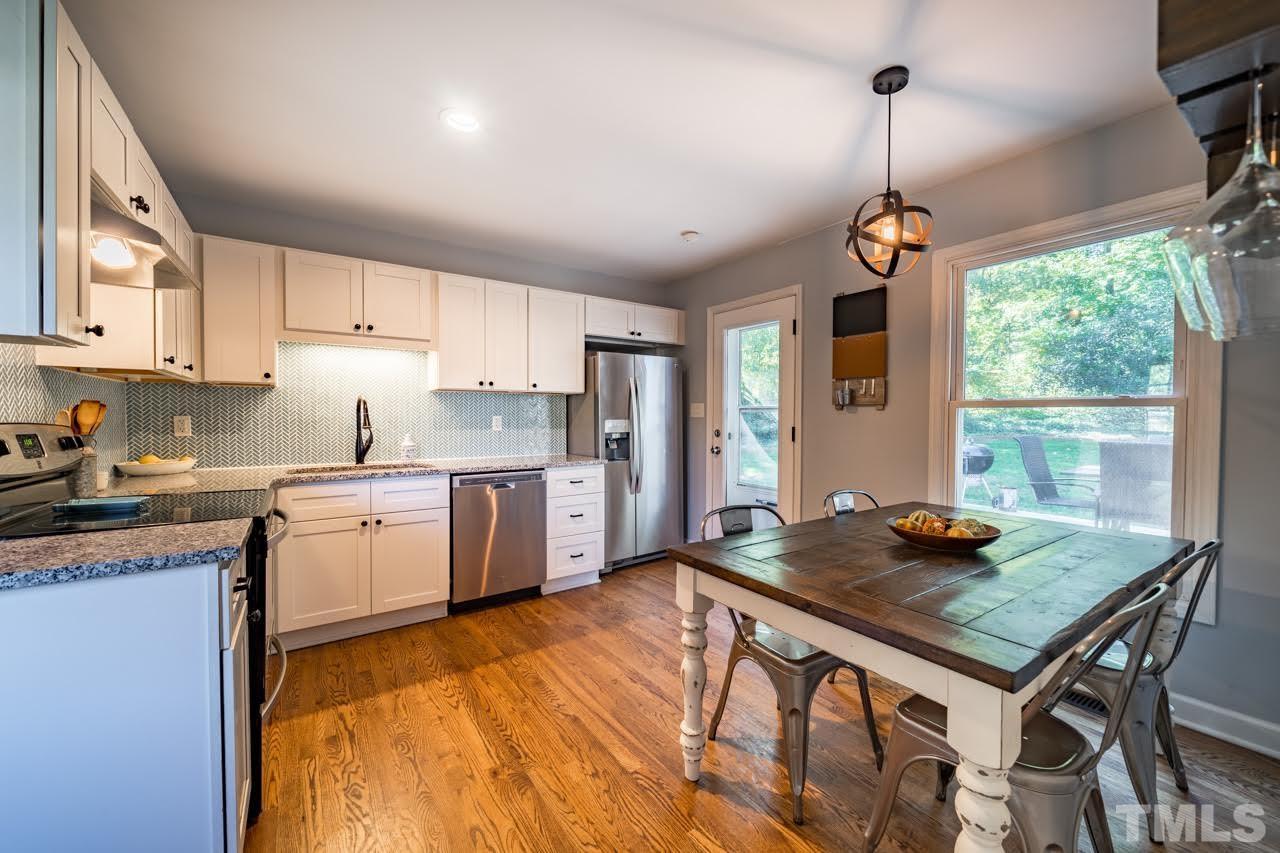 1105 Somerset Road Raleigh, NC 27610 - Photo 8 of 19 a kitchen with stainless steel appliances granite countertop a stove top oven a sink dishwasher a dining table and chairs with wooden floor