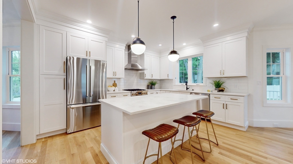 49 Ledge Hill Road Boston, MA 02132 - Photo 4 of 34 a kitchen with stainless steel appliances a stove a sink a refrigerator a dining table and chairs with wooden floor