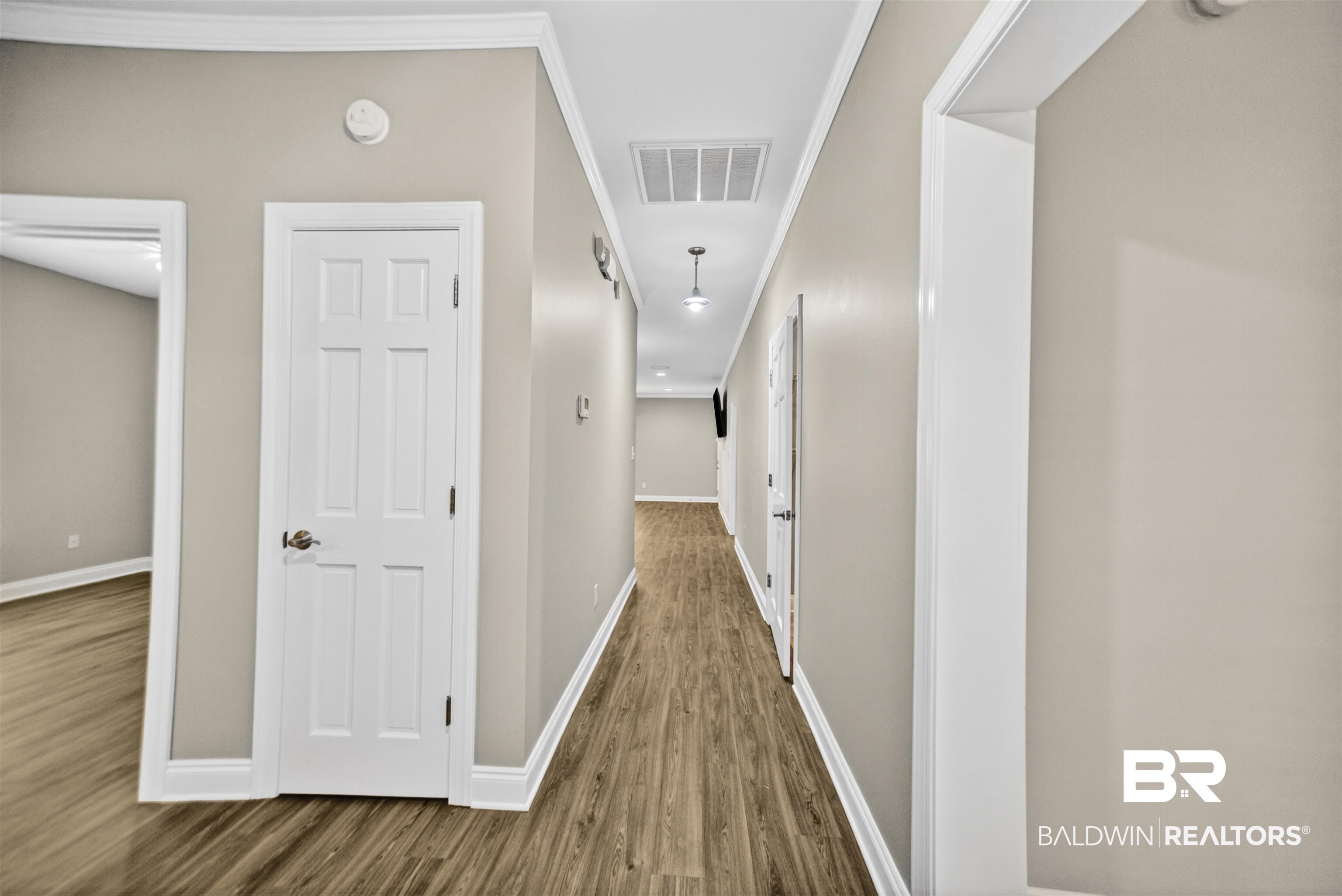 5913 Antoine Road Mobile, AL 36693 - Photo 3 of 33 Hallway featuring wood-finish flooring, light neutral wall paint, white crown molding, and white baseboards