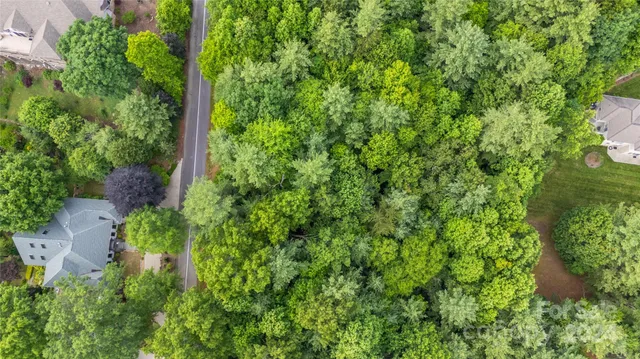 an aerial view of residential house with outdoor space and trees all around