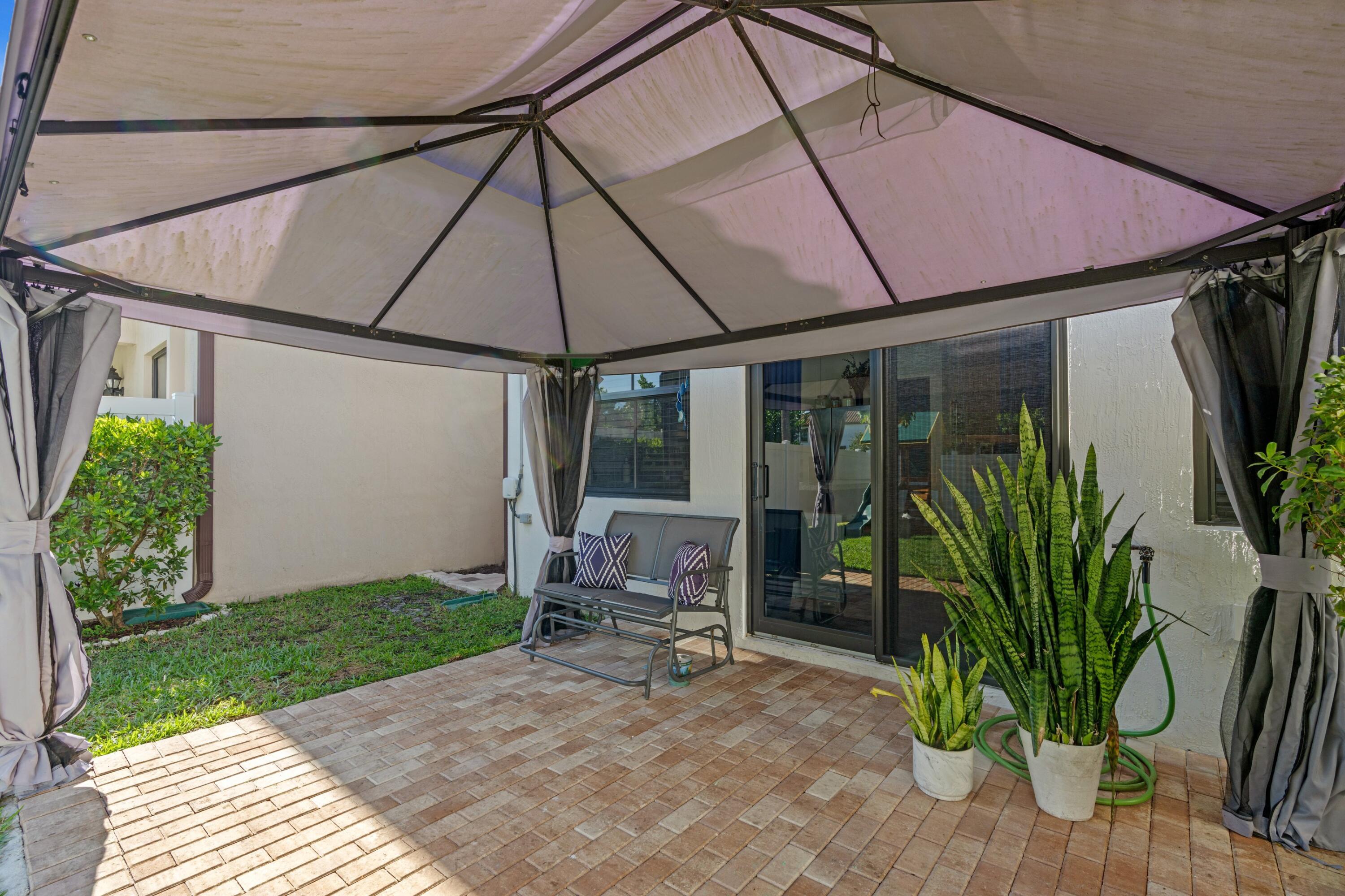 3006 Hoptree Way Riviera Beach, FL 33410 - Photo 22 of 35 a view of a patio with table and chairs under an umbrella