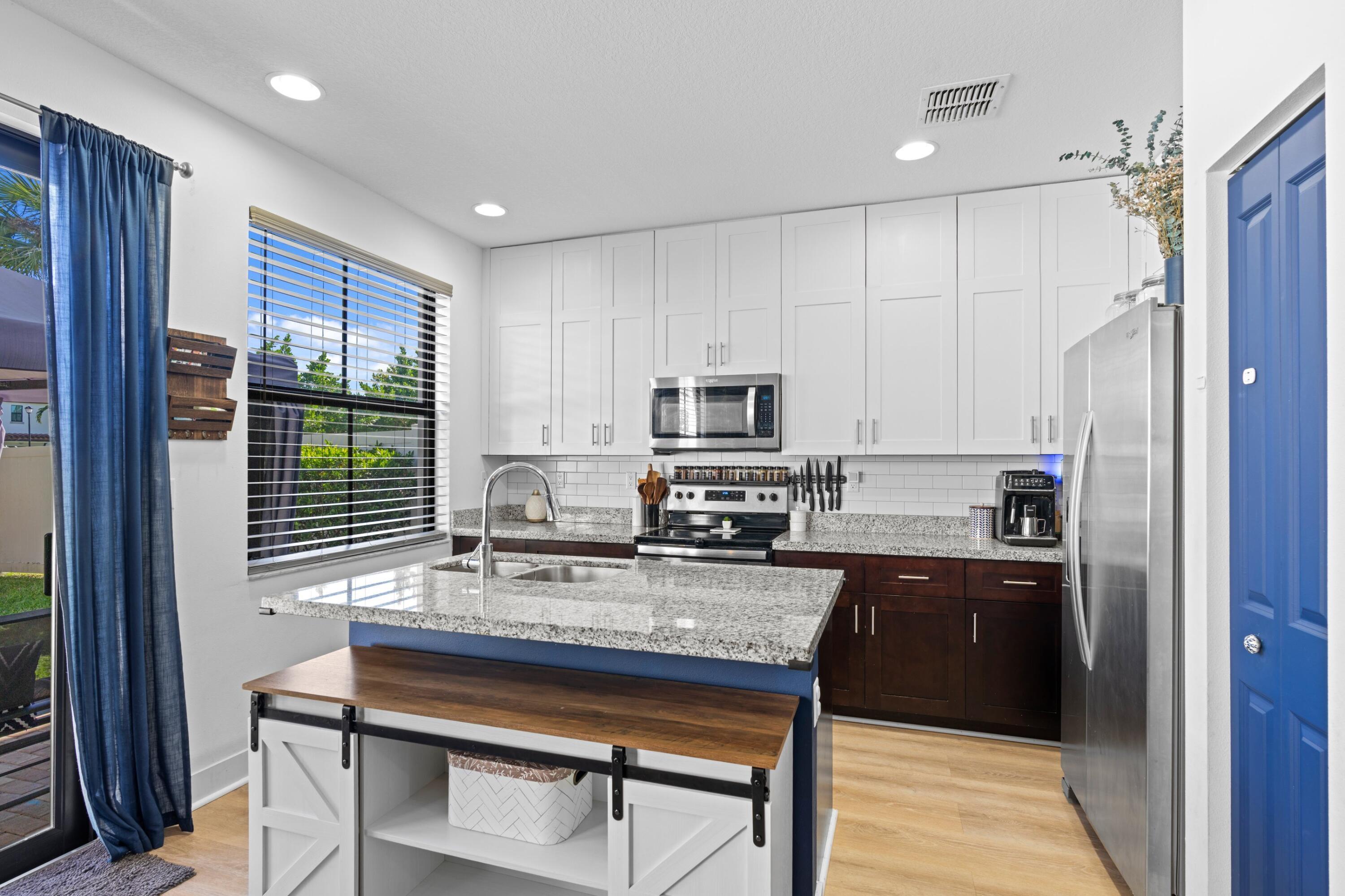 3006 Hoptree Way Riviera Beach, FL 33410 - Photo 9 of 35 a kitchen with kitchen island granite countertop a stove a sink and a refrigerator