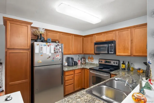 a kitchen with stainless steel appliances granite countertop a refrigerator stove a sink dishwasher and a microwave