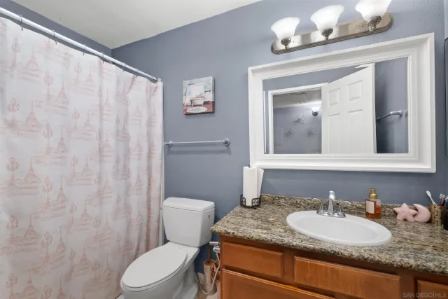 a bathroom with a granite countertop sink mirror vanity and toilet