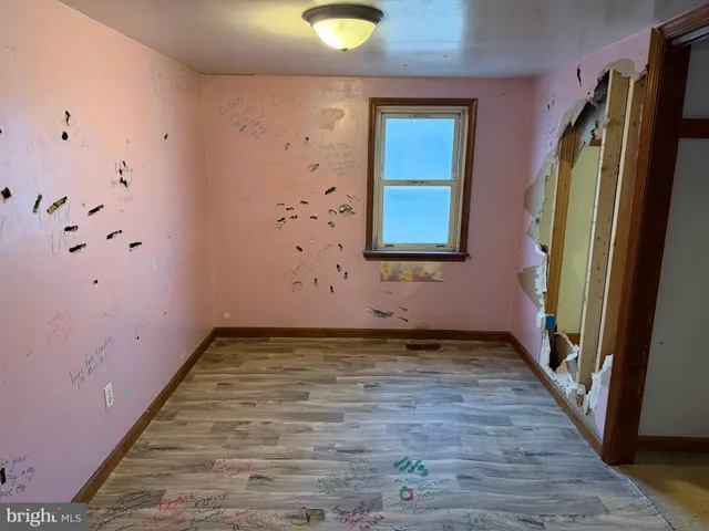 a view of an empty room with window and wooden floor