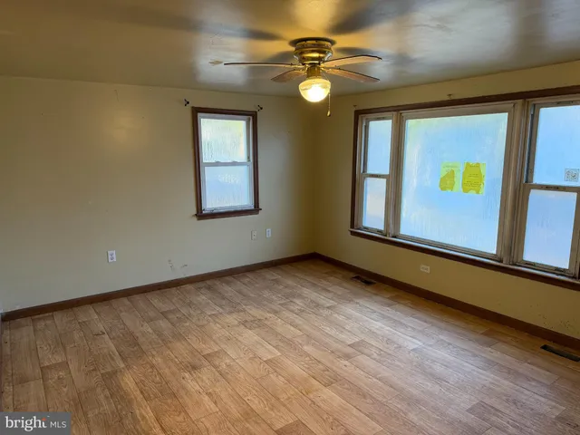 an empty room with windows and fan