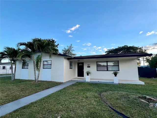 front view of house with a yard and potted plants