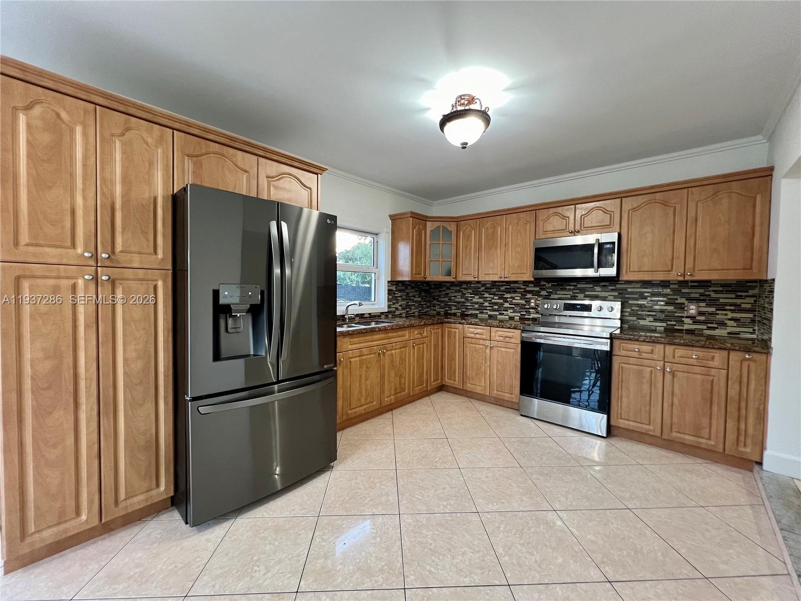 11950 Southwest 199th Street, Unit 1 Miami, FL 33177 - Photo 24 of 30 a kitchen with granite countertop a refrigerator cabinets and stainless steel appliances