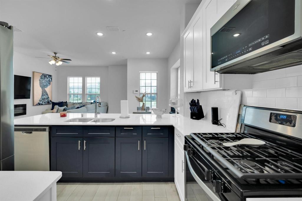 1498 Weston Road Dallas, TX 75234 - Photo 9 of 24 Contemporary kitchen featuring white shaker upper cabinetry and dark lower cabinetry with brushed nickel hardware