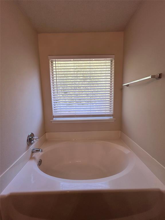 7917 Rattlers Court Arlington, TX 76002 - Photo 18 of 21 a bath tub sitting in a bathroom next to a window