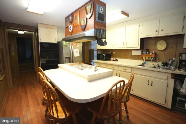 a kitchen with stainless steel appliances kitchen island a table and chairs in it