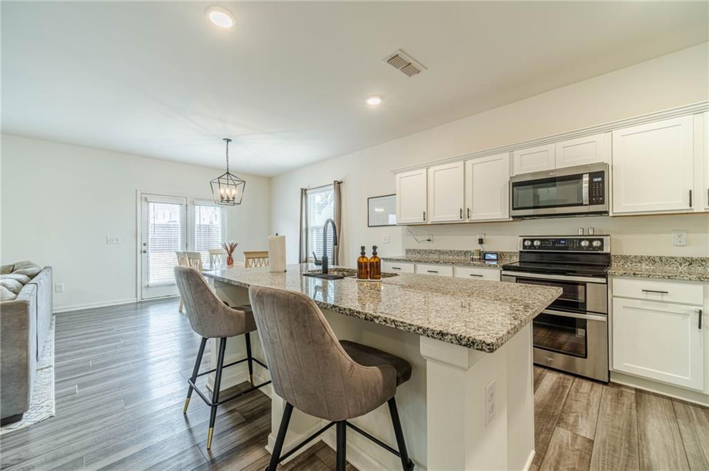 222 Knightsbridge Lane Winder, GA 30680 - Photo 6 of 39 a kitchen with stainless steel appliances granite countertop a stove top oven a sink dishwasher a dining table and chairs with wooden floor