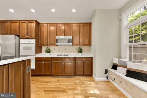 a kitchen with stainless steel appliances granite countertop a stove top oven a refrigerator a sink and dishwasher with wooden floor
