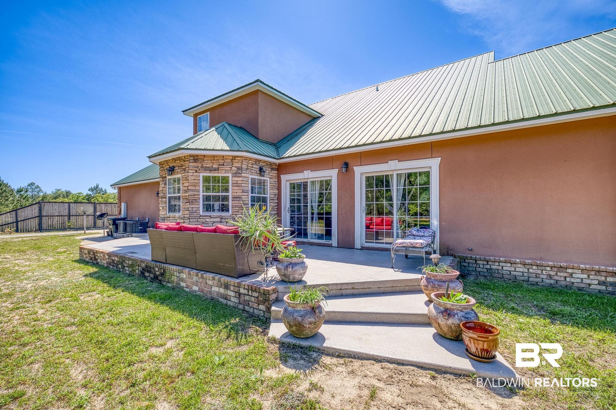 32875 Faircloth Road Lillian, AL 36549 - Photo 59 of 85 Back of house featuring stucco siding, a patio, a metal roof, and an outdoor hangout area
