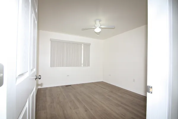 an empty room with wooden floor and ceiling fan