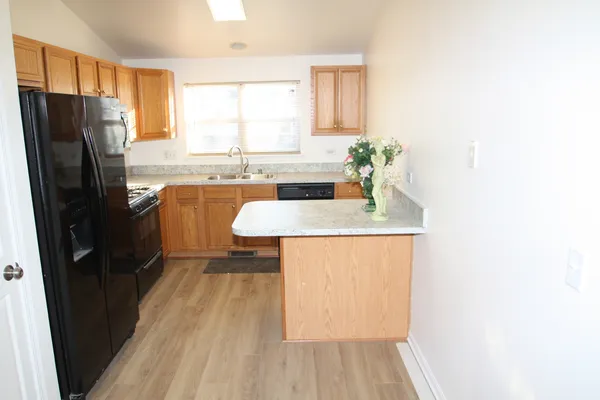 a kitchen with stainless steel appliances granite countertop a refrigerator a sink dishwasher a stove with wooden cabinets and floor