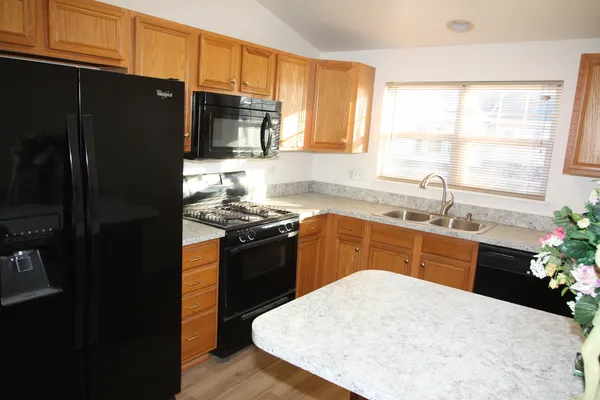 a kitchen with granite countertop a refrigerator stove top oven and sink