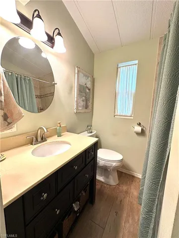 a bathroom with a granite countertop sink mirror vanity and a toilet