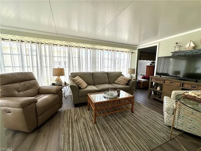 a living room with furniture a flat screen tv and a large window