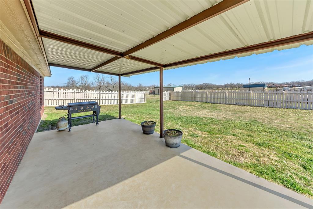 512 Allison Road Springtown, TX 76082 - Photo 19 of 32 a view of a patio with a table chairs under an umbrella