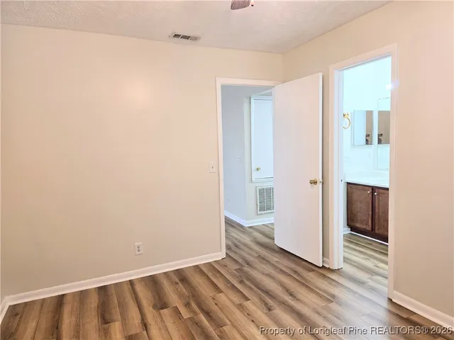 a view of an empty room with wooden floor and a bathroom