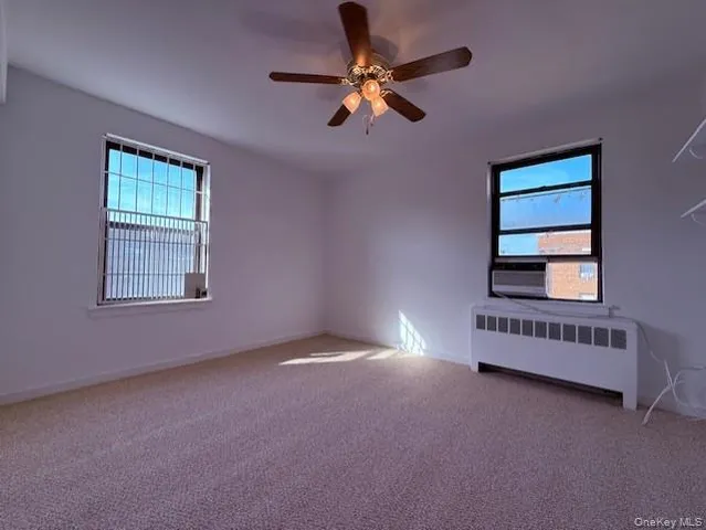 an empty room with windows and ceiling fan