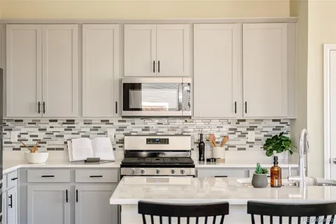 a kitchen with stainless steel appliances a sink a stove and white cabinets