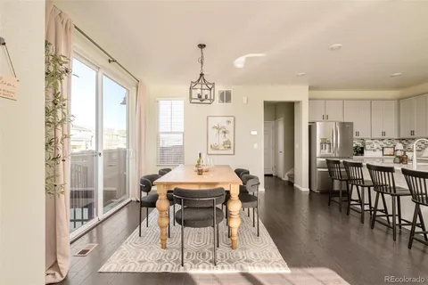 a dining room with wooden floor a chandelier a glass table and chairs