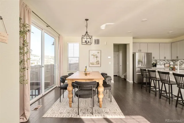a dining room with wooden floor a chandelier a glass table and chairs