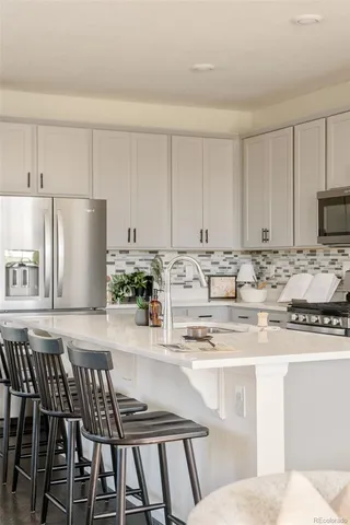 a kitchen with stainless steel appliances granite countertop a stove a sink a refrigerator and white cabinets