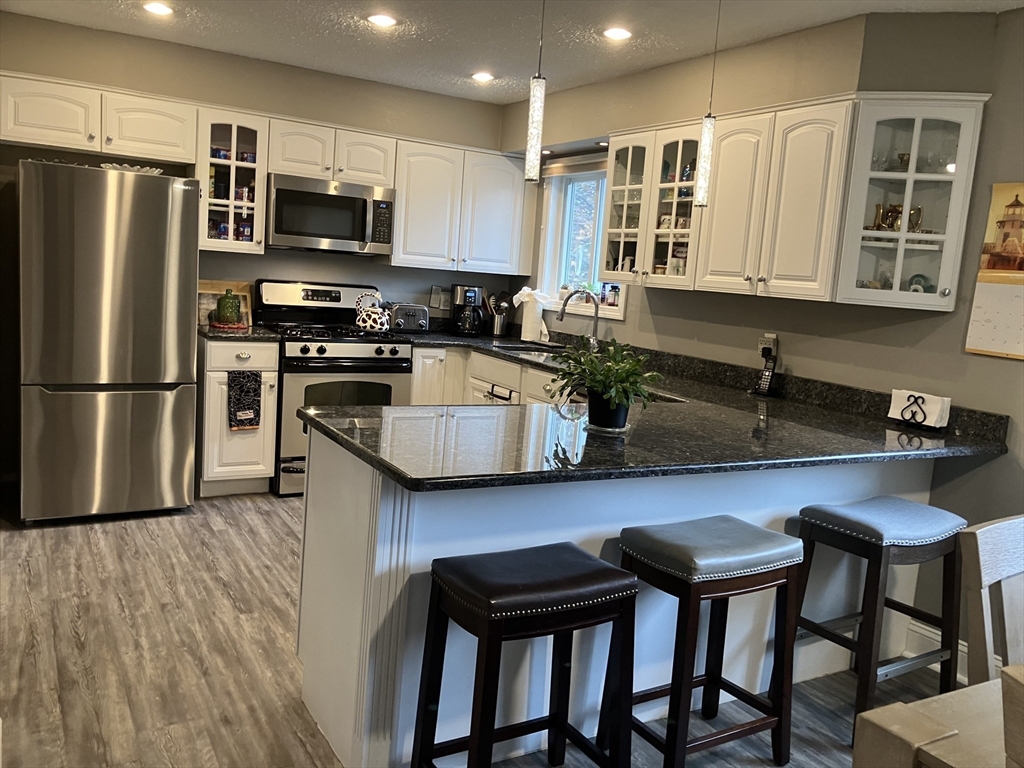 255 North Road, Unit 65 Chelmsford, MA 01824 - Photo 8 of 31 a kitchen with granite countertop a table chairs microwave and refrigerator