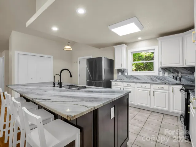 a kitchen with granite countertop stainless steel appliances a sink stove and cabinets