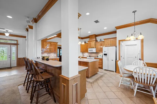 a kitchen with a stove a sink a kitchen island with chairs and wooden cabinets