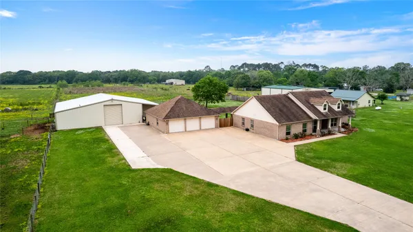 an aerial view of a house with green yard and large trees