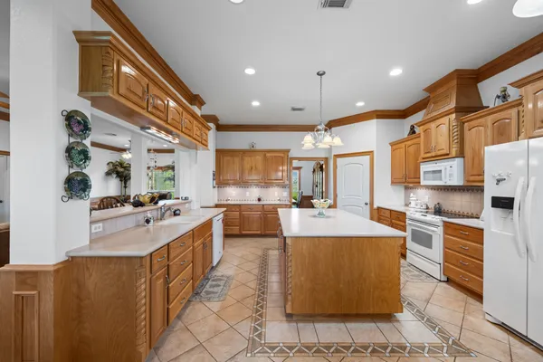 a kitchen with stainless steel appliances kitchen island granite countertop dining table chairs and white cabinets