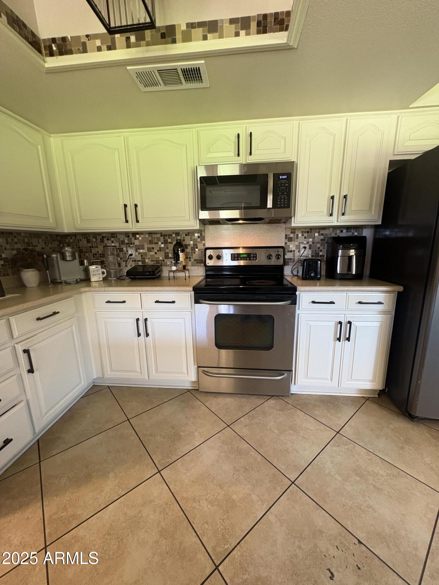 5021 West Echo Lane Glendale, AZ 85302 - Photo 2 of 7 a kitchen with stainless steel appliances kitchen island granite countertop a sink a stove top oven and white cabinets