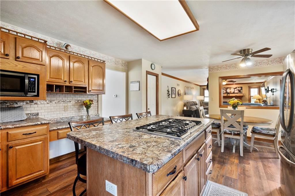 106 Good Luck Lane Mars, PA 16046 - Photo 11 of 33 a kitchen with a stove a sink a kitchen island with chairs and wooden cabinets