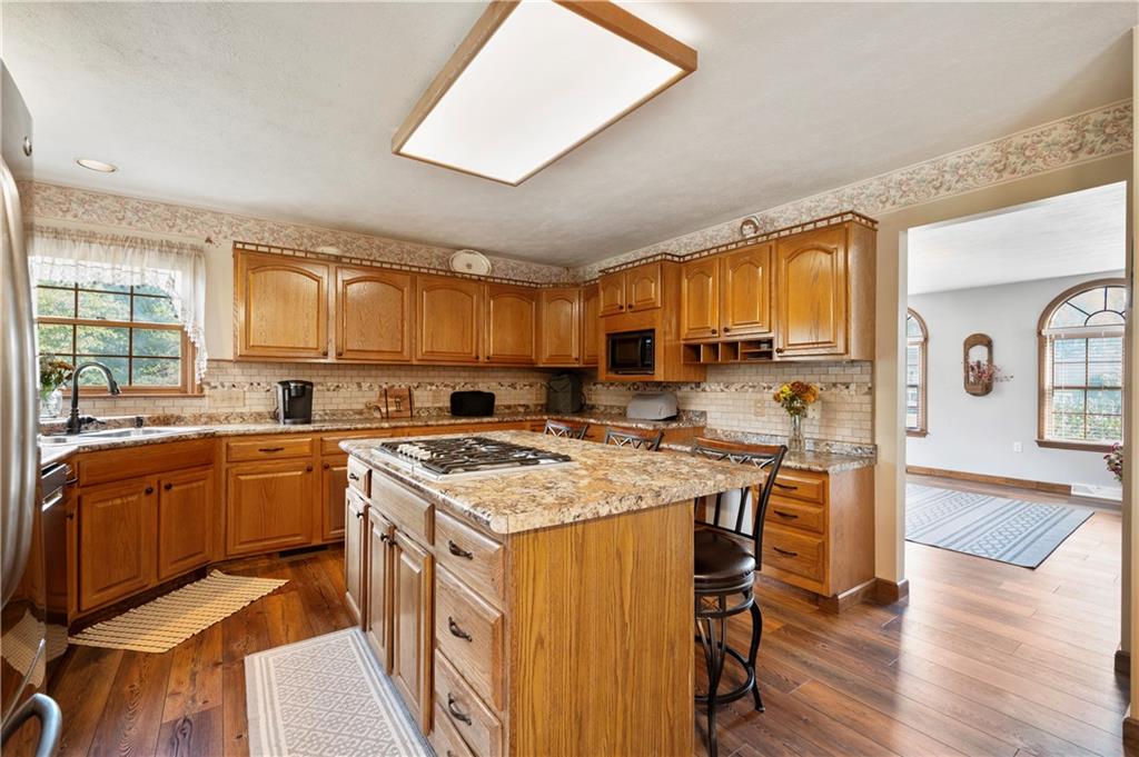 106 Good Luck Lane Mars, PA 16046 - Photo 9 of 33 a kitchen with stainless steel appliances granite countertop a stove top oven a sink dishwasher a dining table and chairs with wooden floor