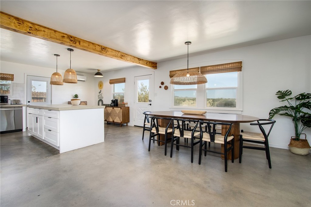 64975 Sun Oro Road Joshua Tree, CA 92252 - Photo 17 of 52 a kitchen with kitchen island a dining table chairs sink and white cabinets
